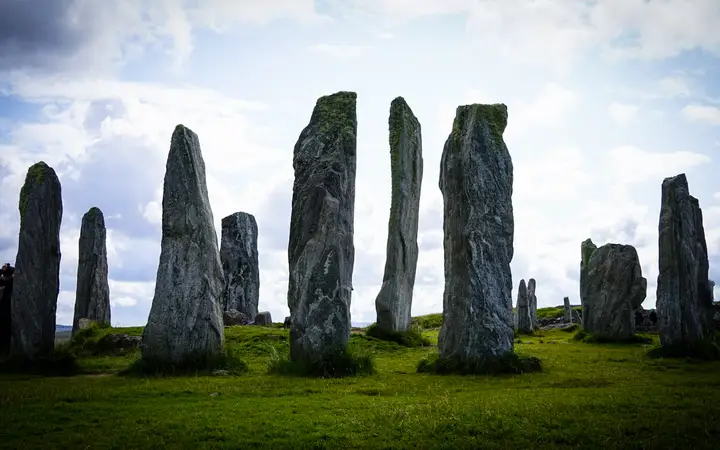 Tall slabs of the Calanais standing stones on a grassy ridge on the Isle of Lewis