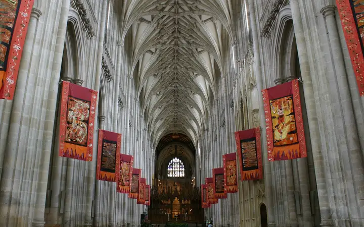 The long nave of Winchester Cathedral hung with flags